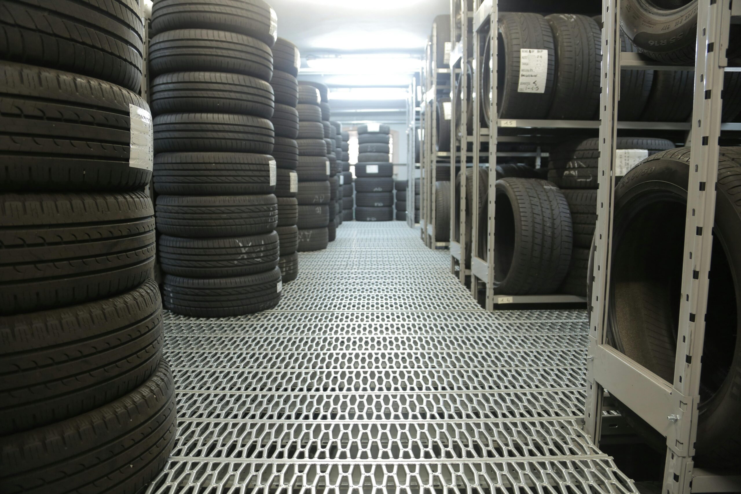 Rows of stacked tires in an indoor industrial warehouse for storage.